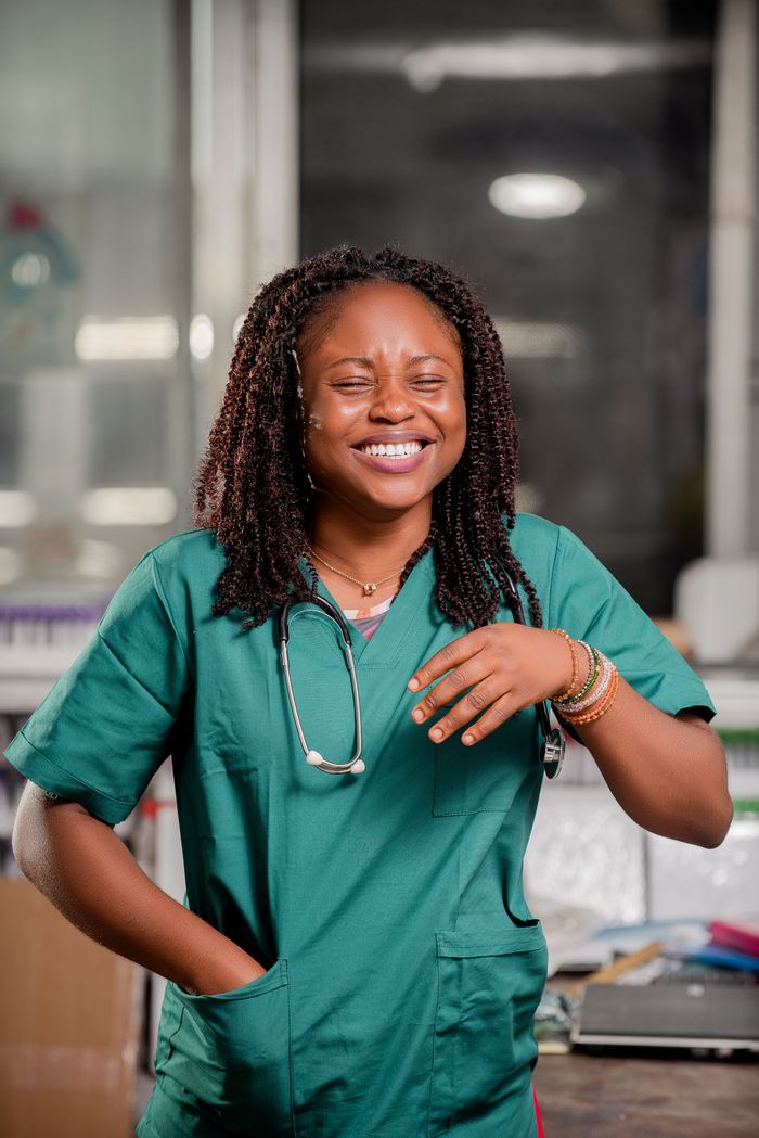 Smiling healthcare worker with stethoscope in a clinic setting, representing positivity and professionalism.